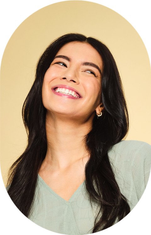 A woman is looking up to the right smiling.