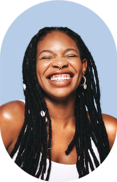 A woman with long hair is smiling and scrunching her face.