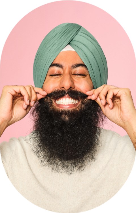 A man is smiling largely and twirling his mustache.