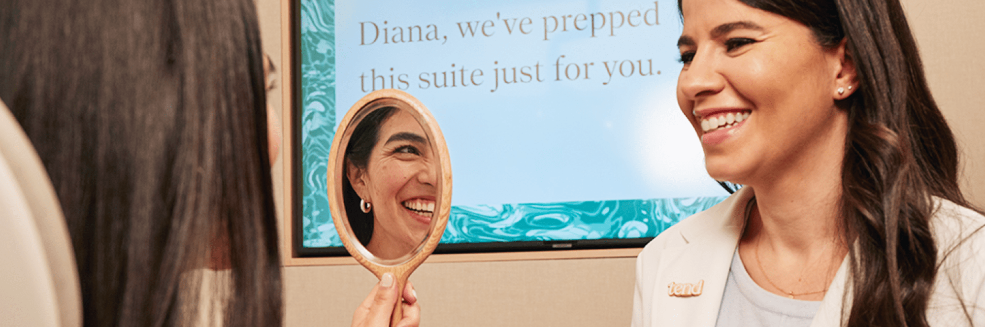 A patient admites their smile as a team member looks on.