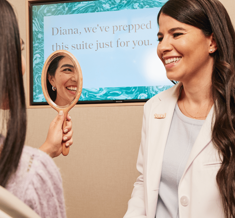 A patient admites their smile as a team member looks on.