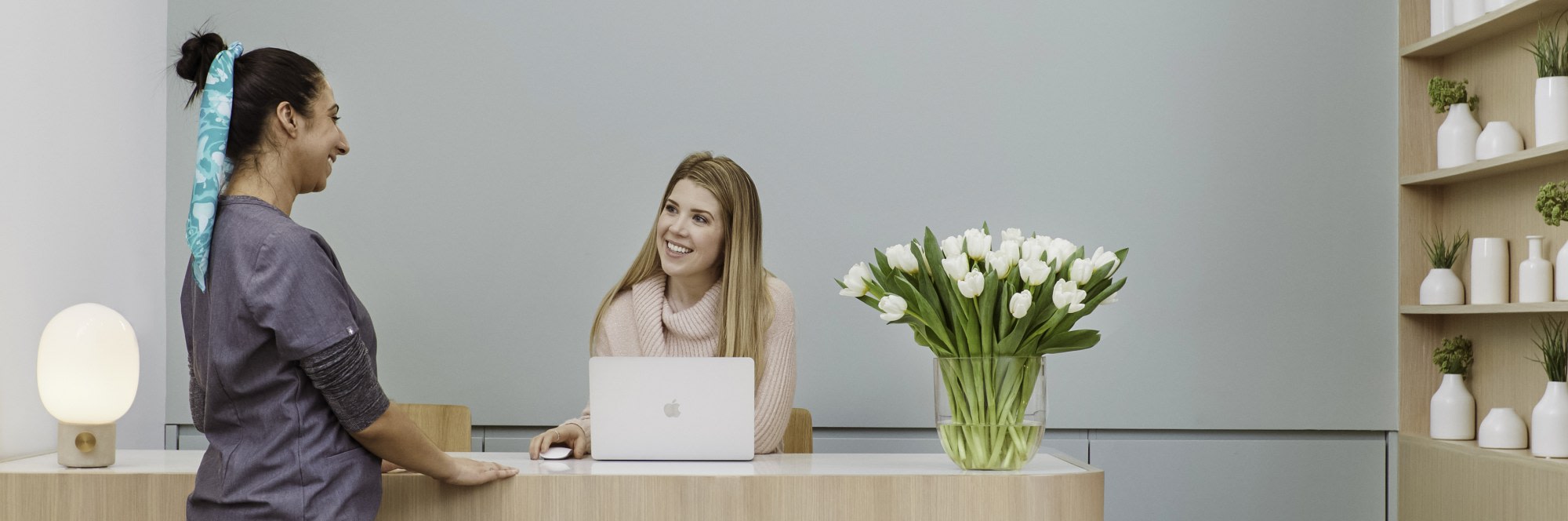 Dental professional and receptionist talking at reception desk.