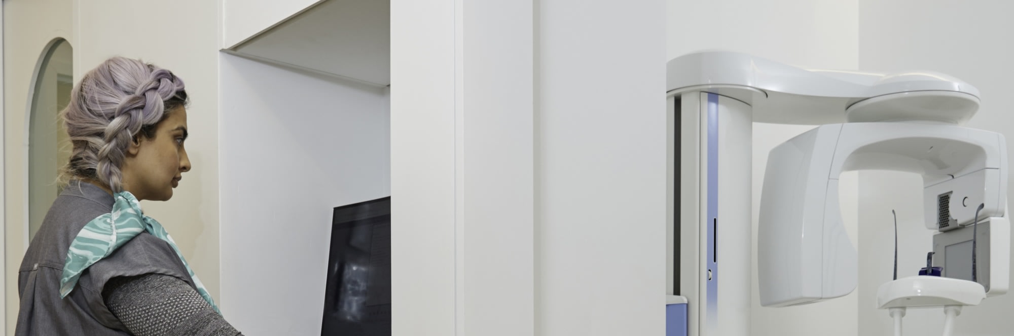 X-ray machine room and dental professional looking at X-ray.