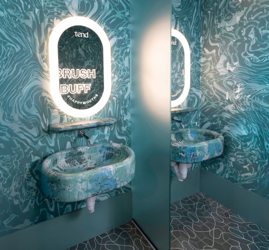 Sink and mirror in teeth brushing area at dental studio.