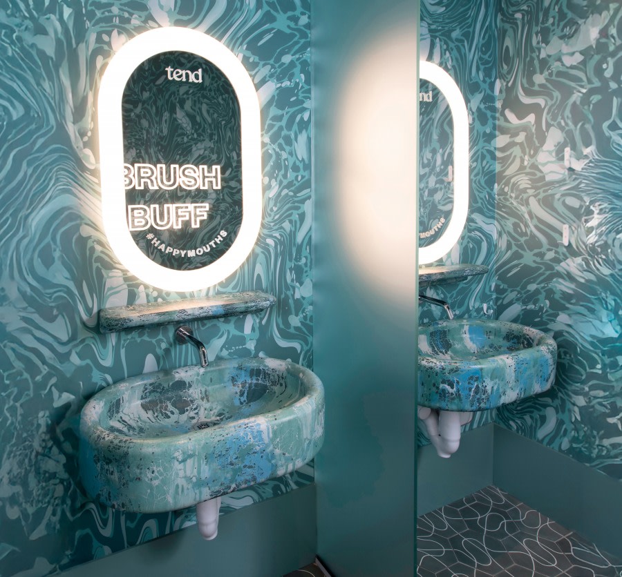 Mirror and sink in teeth brushing area at dental studio.