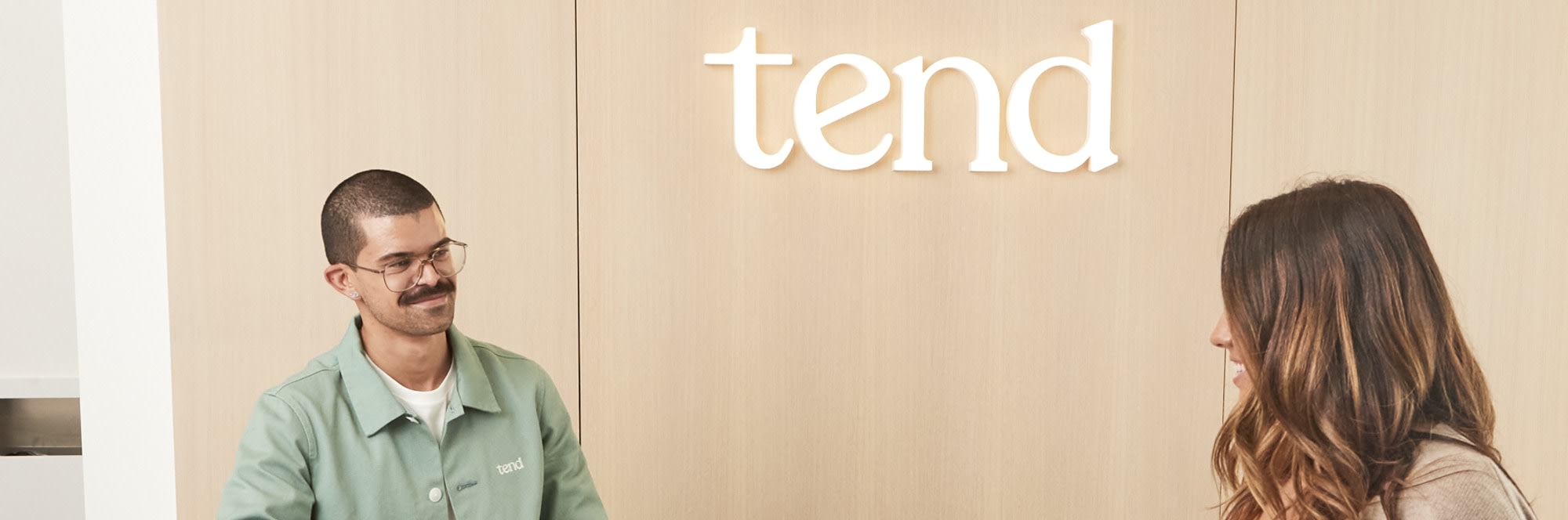 Patient walking past dental professional at reception desk.