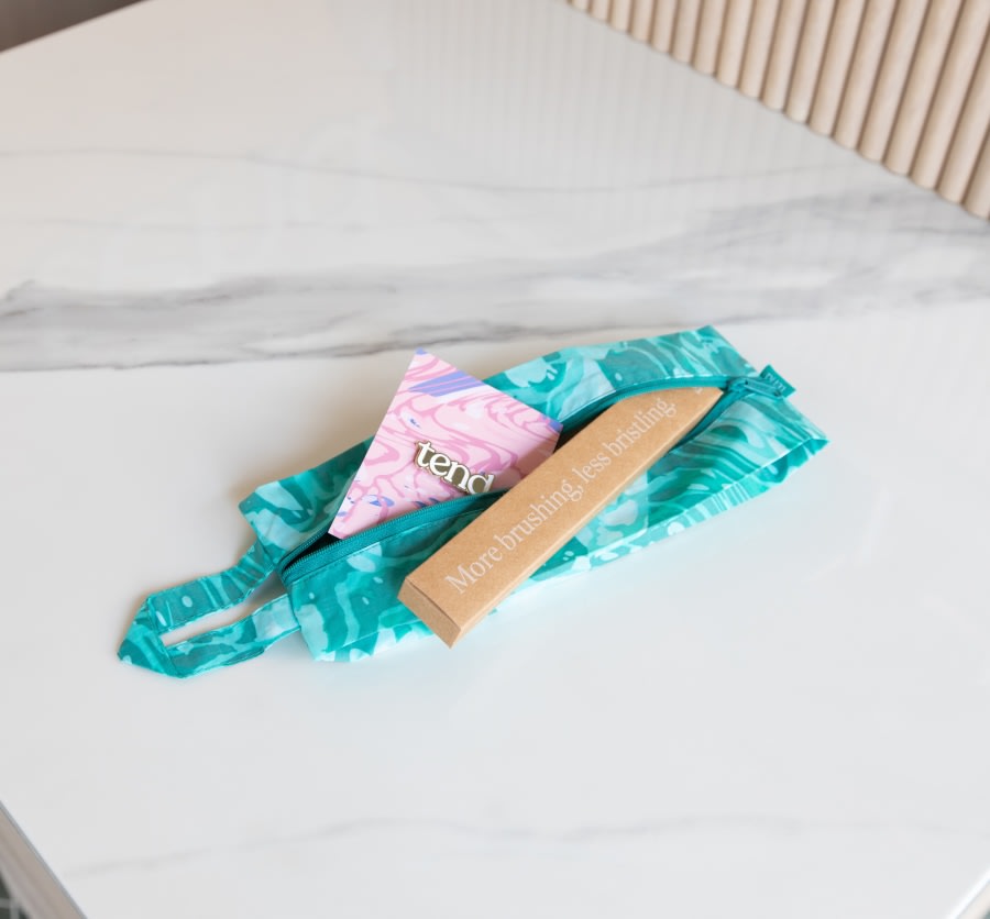 Blue zippered brush bag with toothbrush and business card.