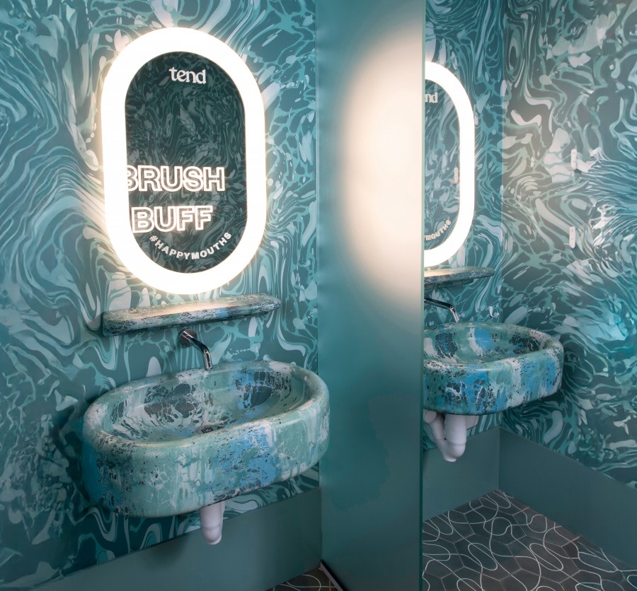 Mirror and sink in teeth brushing area at dental studio.