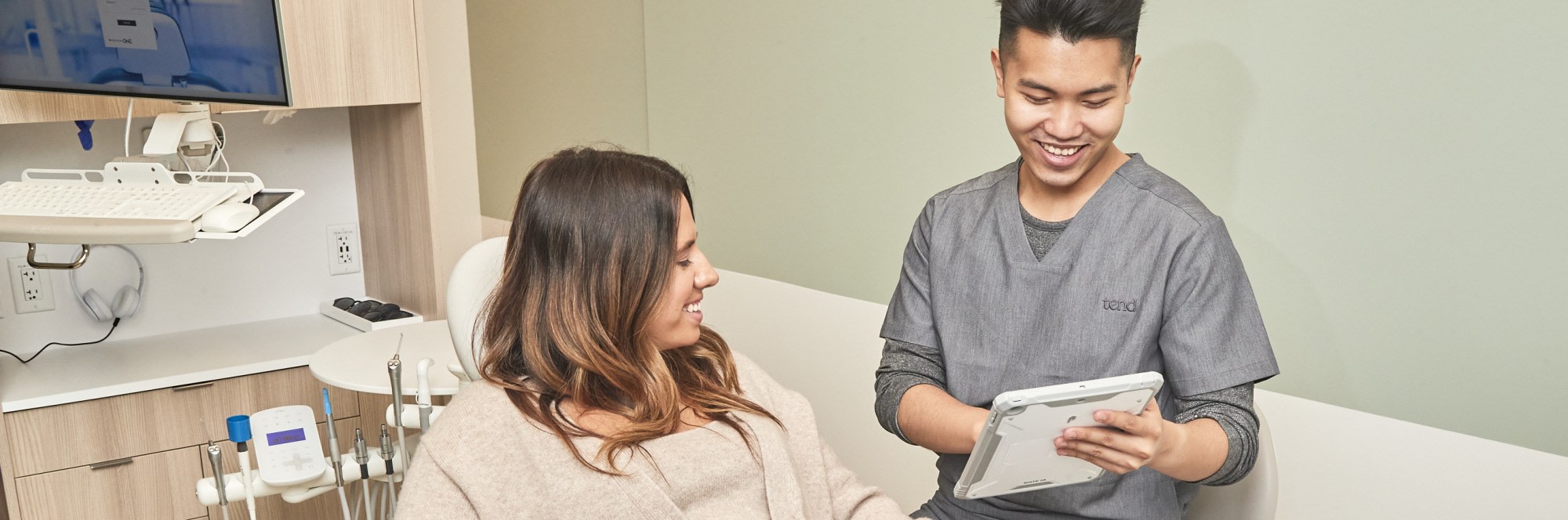 A team member shows a patient something on a tablet.