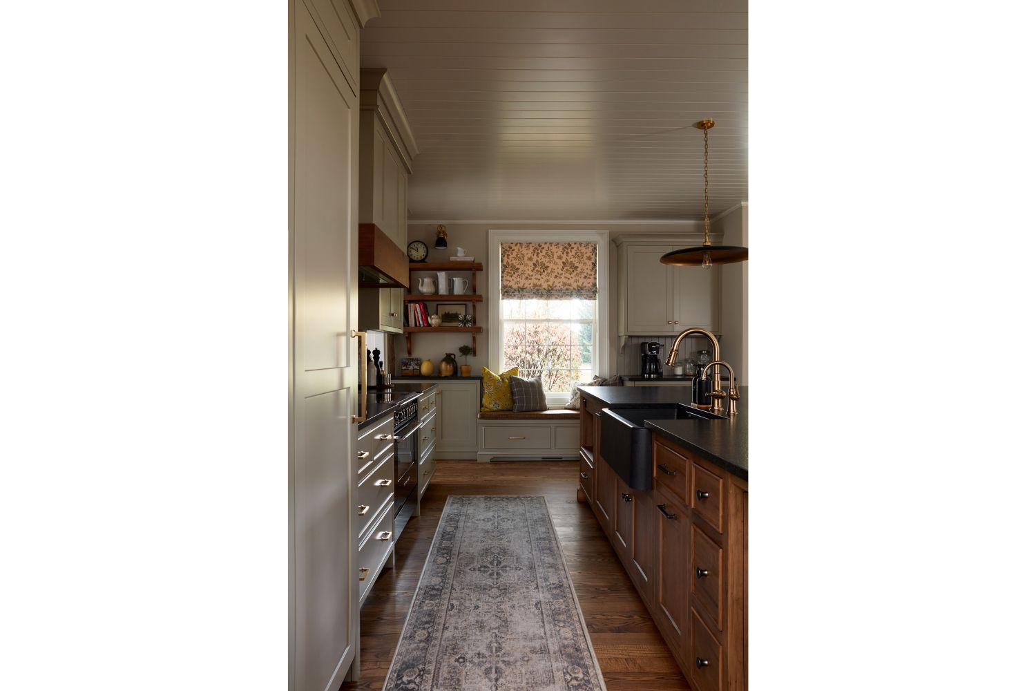 View of painted gray kitchen cabinets and maple window seating