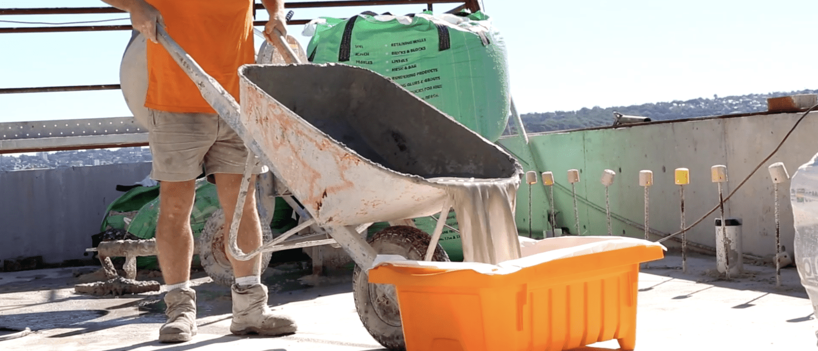 Man dumping wheel barrow of construction slurry into a slurrytub