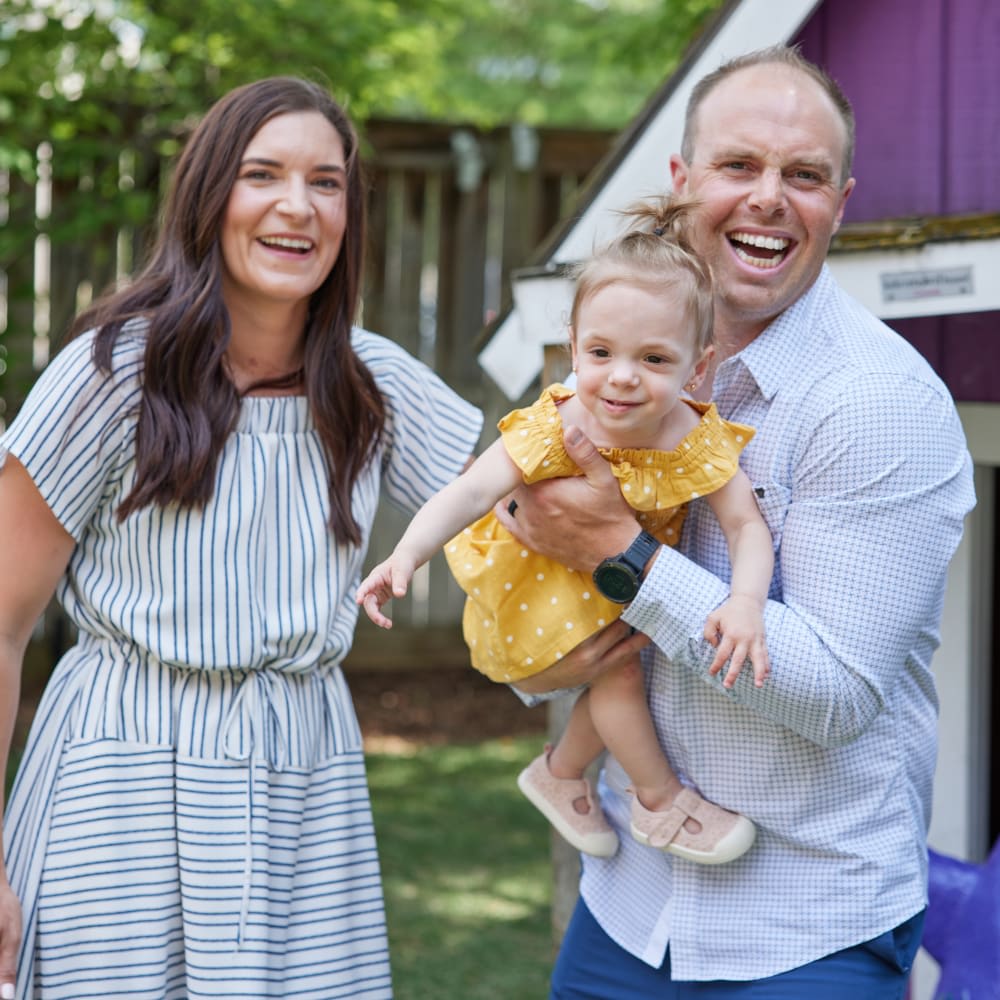 Family of three outside. Dad lifting baby girl.