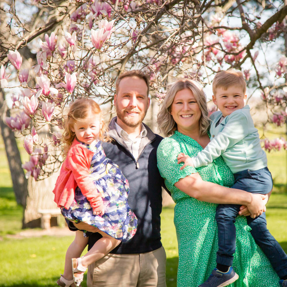 Family of four smiling outside in field