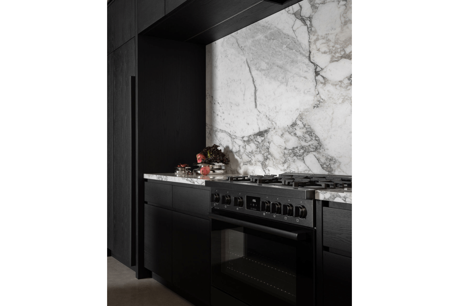 Moody kitchen design with black cabinets and stone backsplash