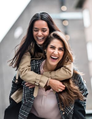Two women laughing together, one playfully carrying the other 