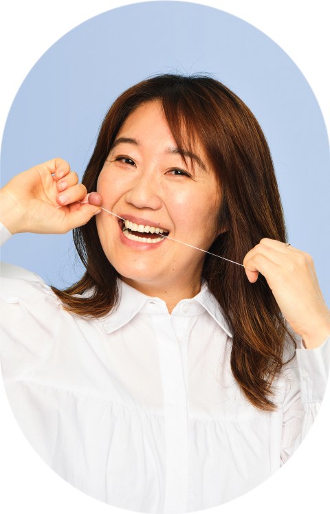 A woman flosses her teeth.