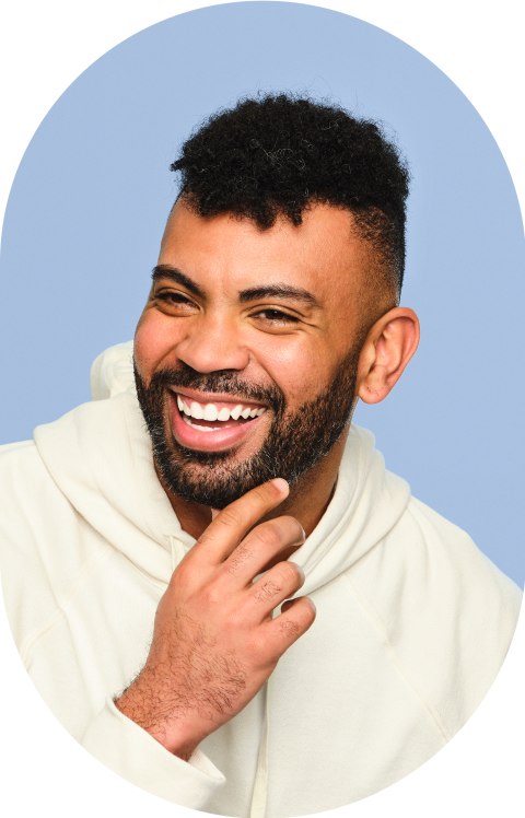 A man is smiling and has his hand on his chin.