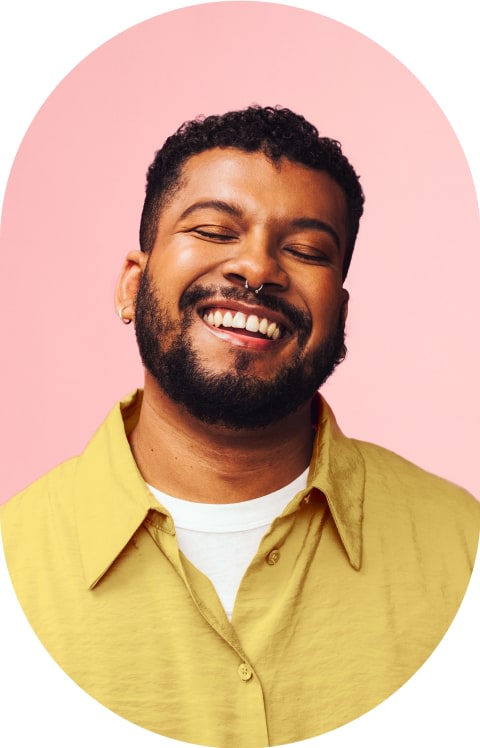 A man with a septum piercing is smiling with his eyes closed.