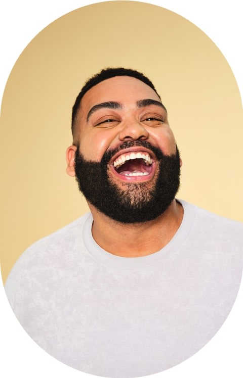 A man with a beard is laughing with his mouth open.