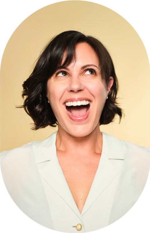 A woman with a short bob is smiling largely and looking up.