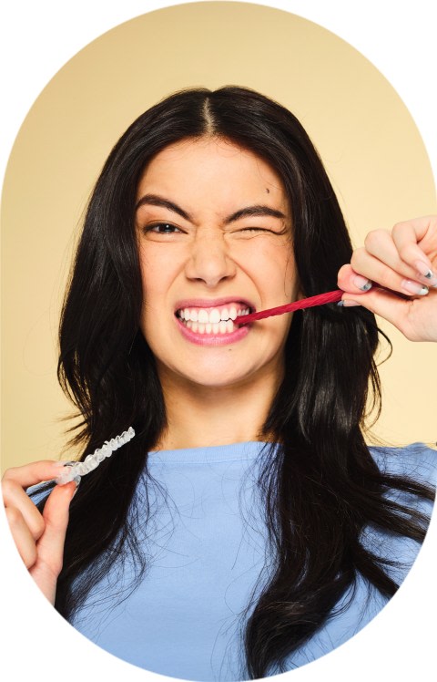 A woman is pulling a piece of licorice out of her mouth.