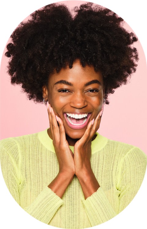 A woman smiles with her hands on her cheeks.