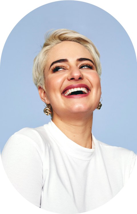 A blonde woman with short hair is smiling and looking left.