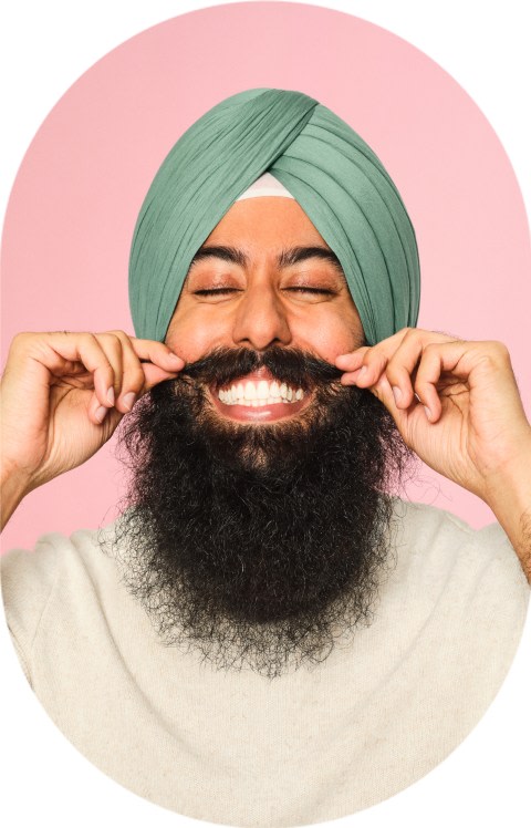 A man with a long beard is twirling his mustache.