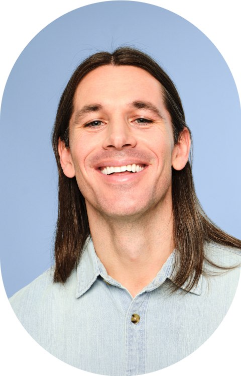 A man with long straight hair is smiling.