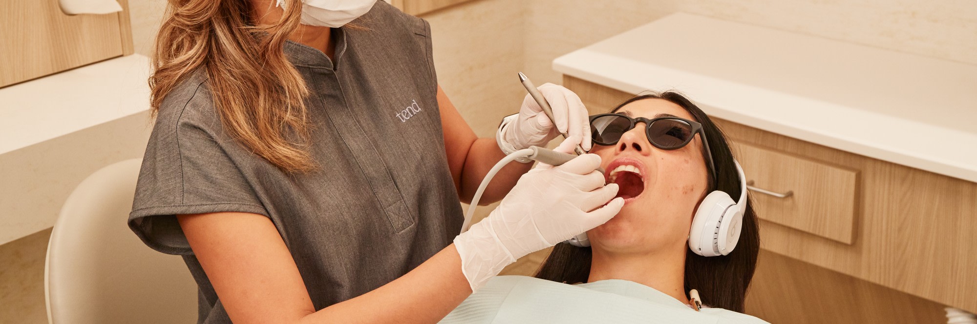A team member performs a dental exam on a patient.