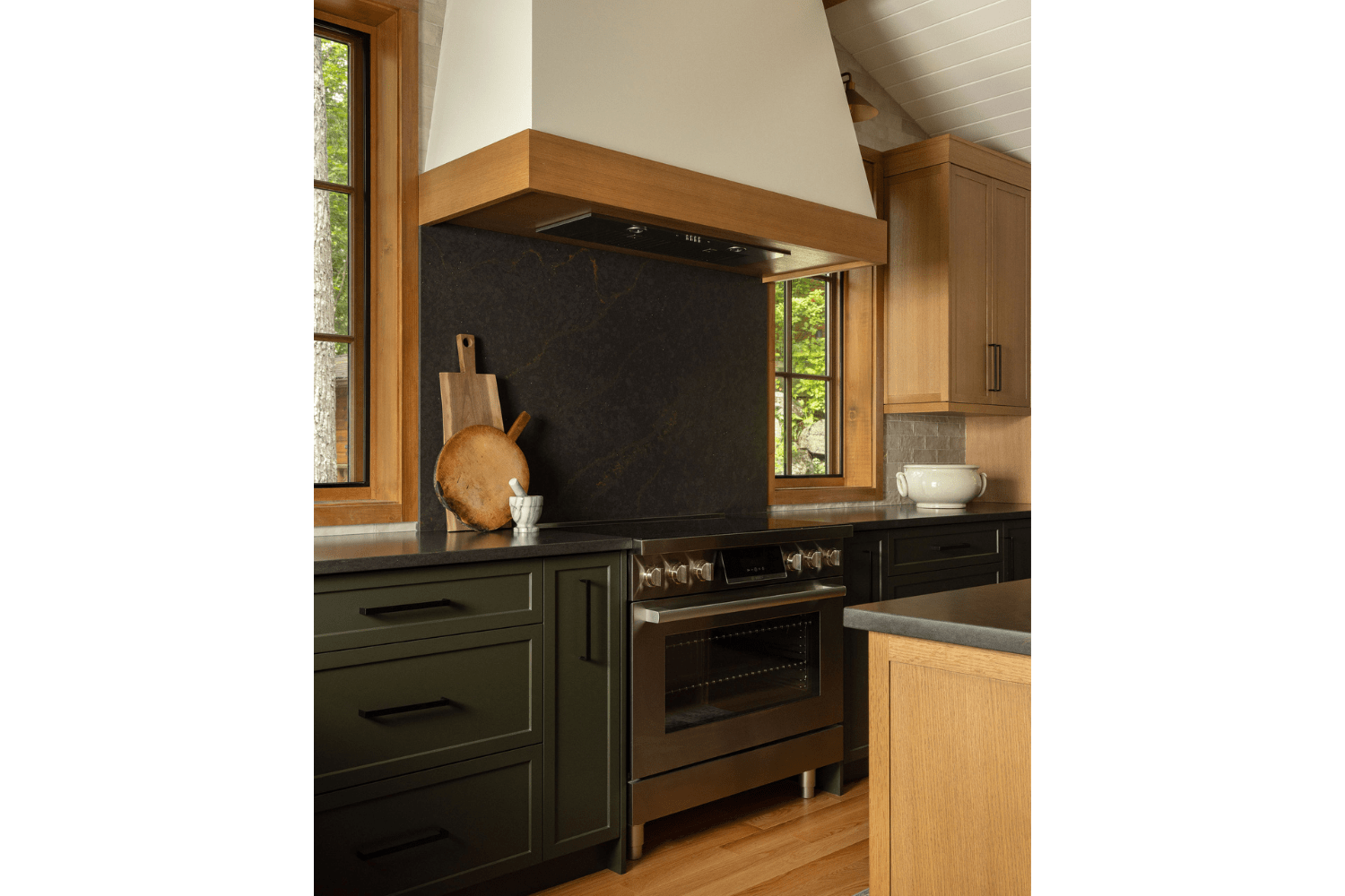 Earthy kitchen with green cabinetry and custom white range hood