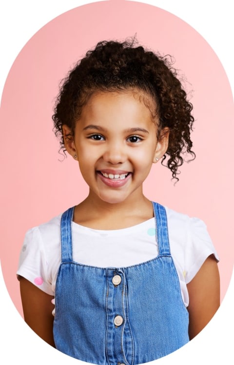 A little girl is standing and smiling.