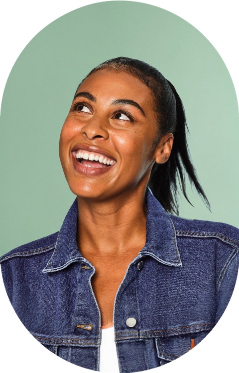 A woman in denim jacket is smiling and looking up.