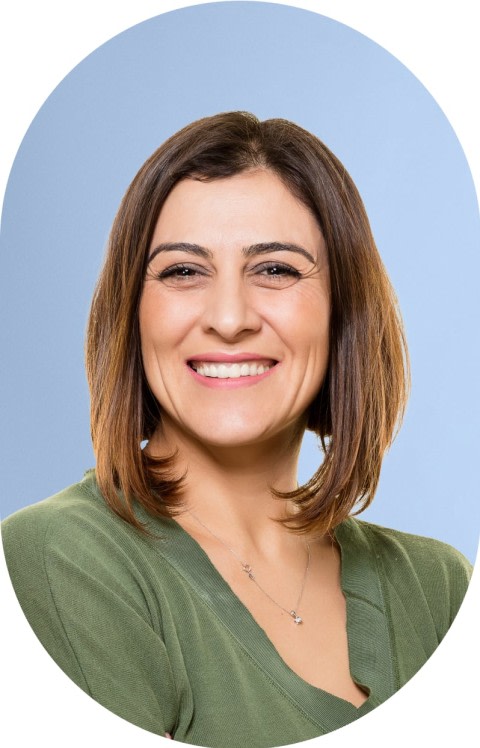 An older woman in a green shirt is smiling