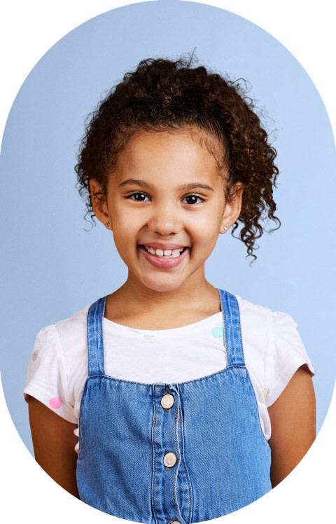 A little girl is standing and smiling.