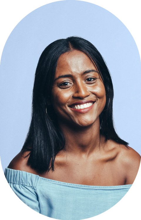 A woman in a blue off-the-shoulder shirt is smiling.