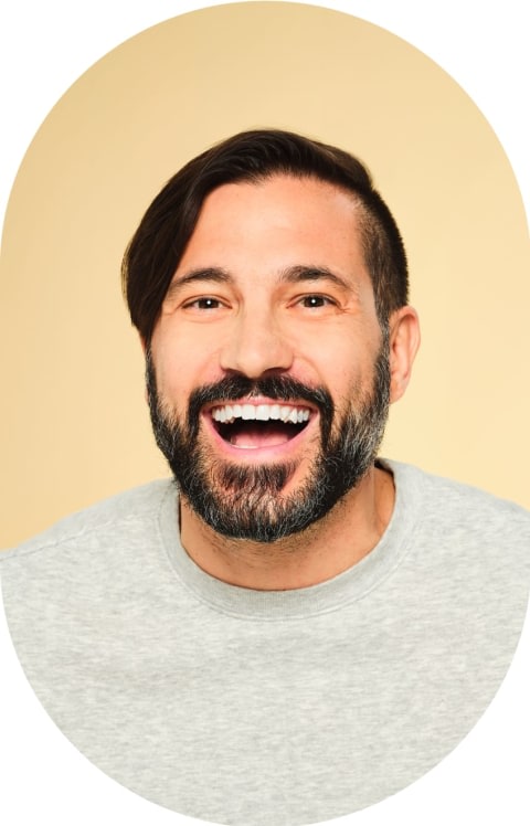 A man with short dark hair leans forward smiling.