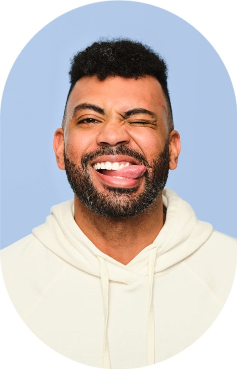 Man with dark hair and a beard smiling with his tongue out.