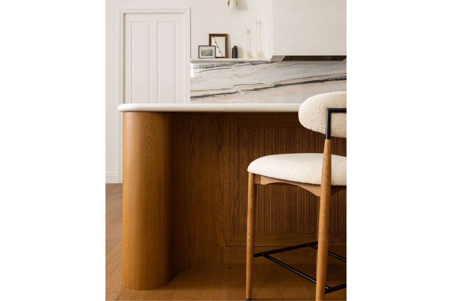 Custom warm oak kitchen island with curved posts and reeded door