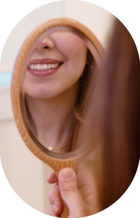 A patient is looking at their smile in the mirror.