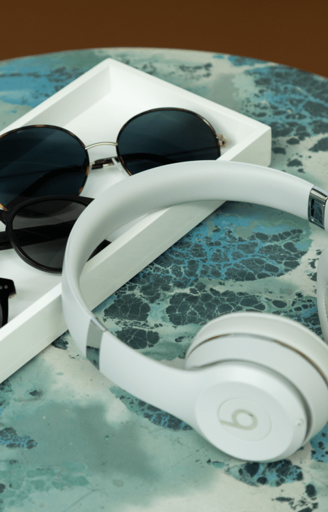 A pair of headphones and sunglasses sit on a tray.