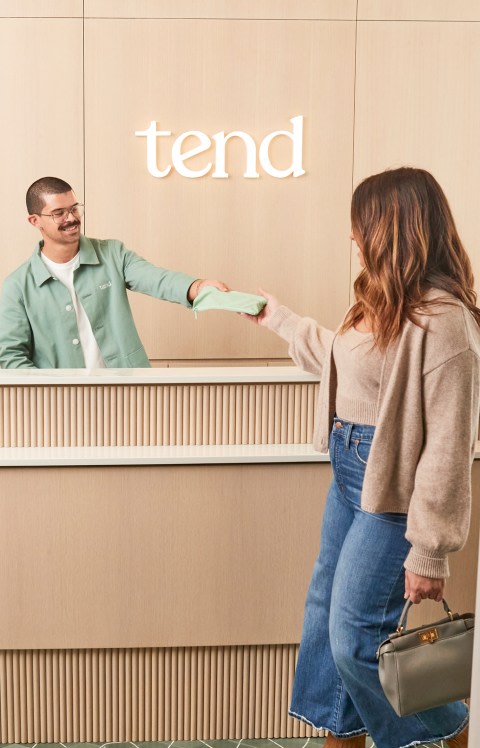 A Tend employee passes a guest a brush bag.