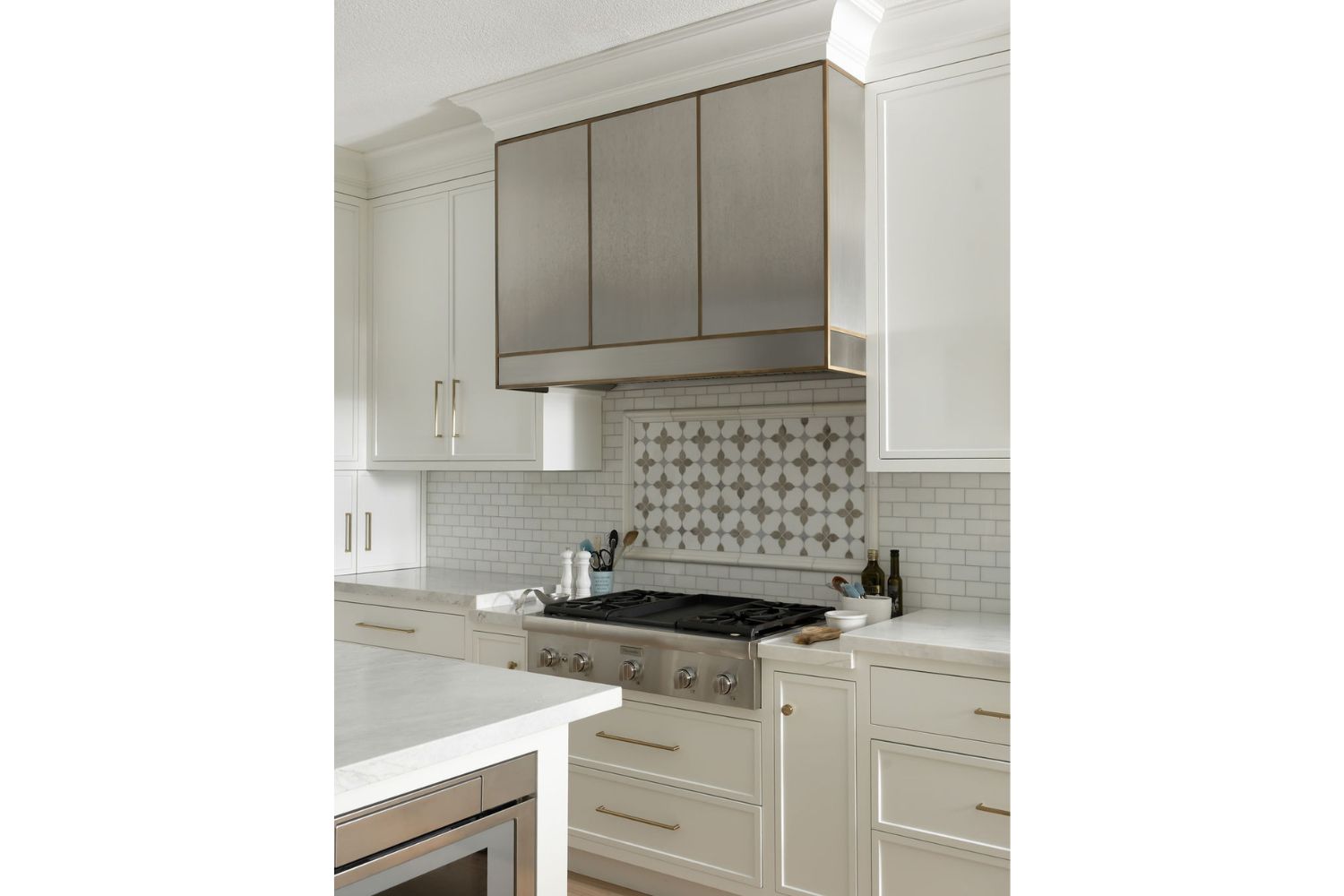 Custom stainless steel range hood over gas range in white kitche